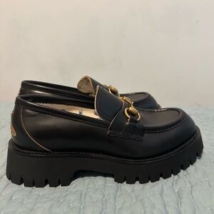 Black and gold Gucci Harald loafers with a chunky heel and gold buckles